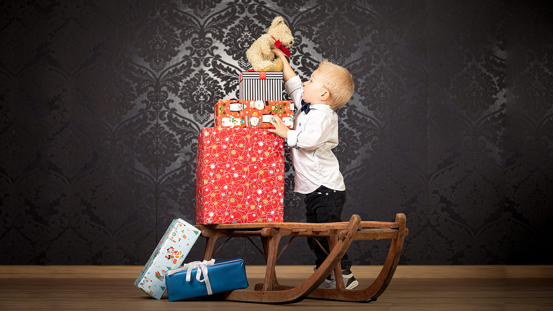 Birkenstudio Kind mit Weihnachtsgeschenken auf Schlitten